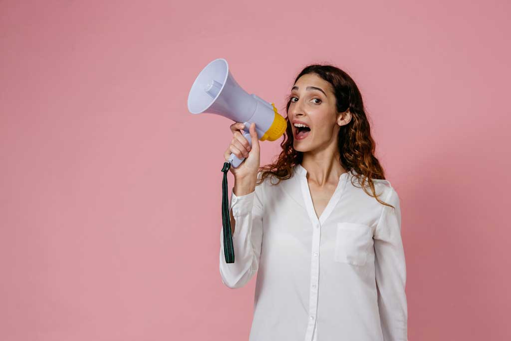 Woman in White Button Up Long Sleeve Shirt Holding a Megaphone