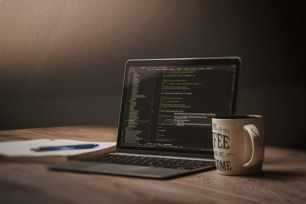 Laptop screen displaying code with coffee mug