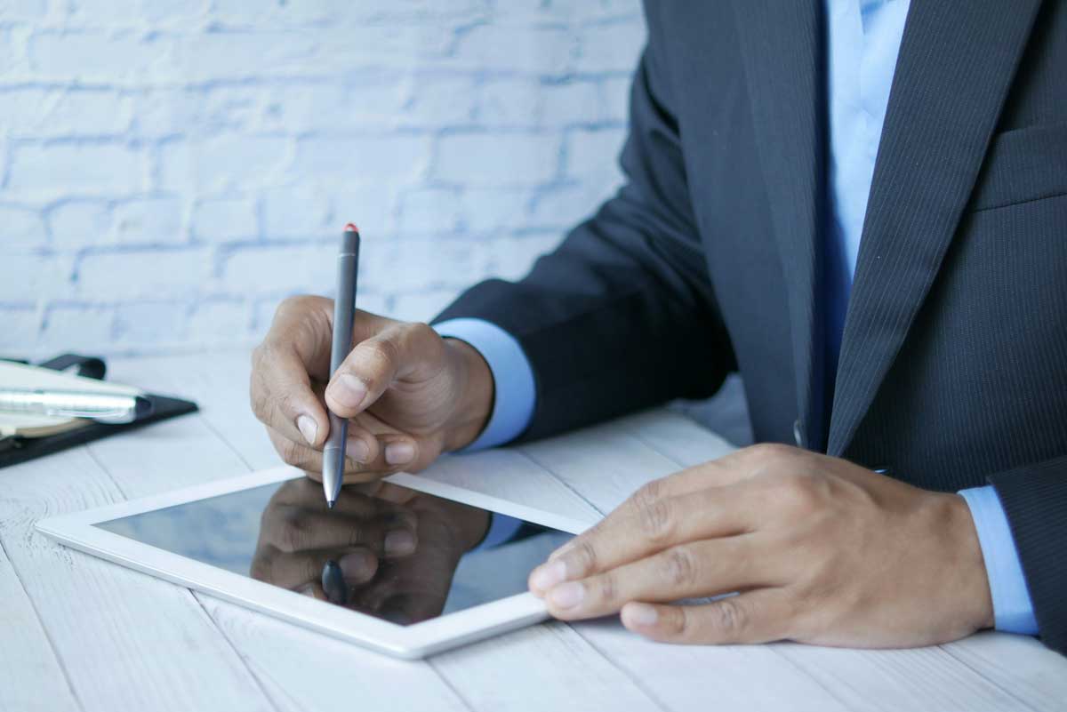 Man in a suit writing on a tablet