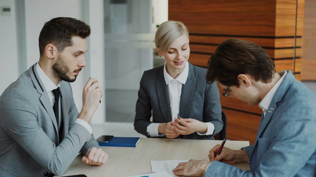 Young businessman in suit signing contract with his colleague