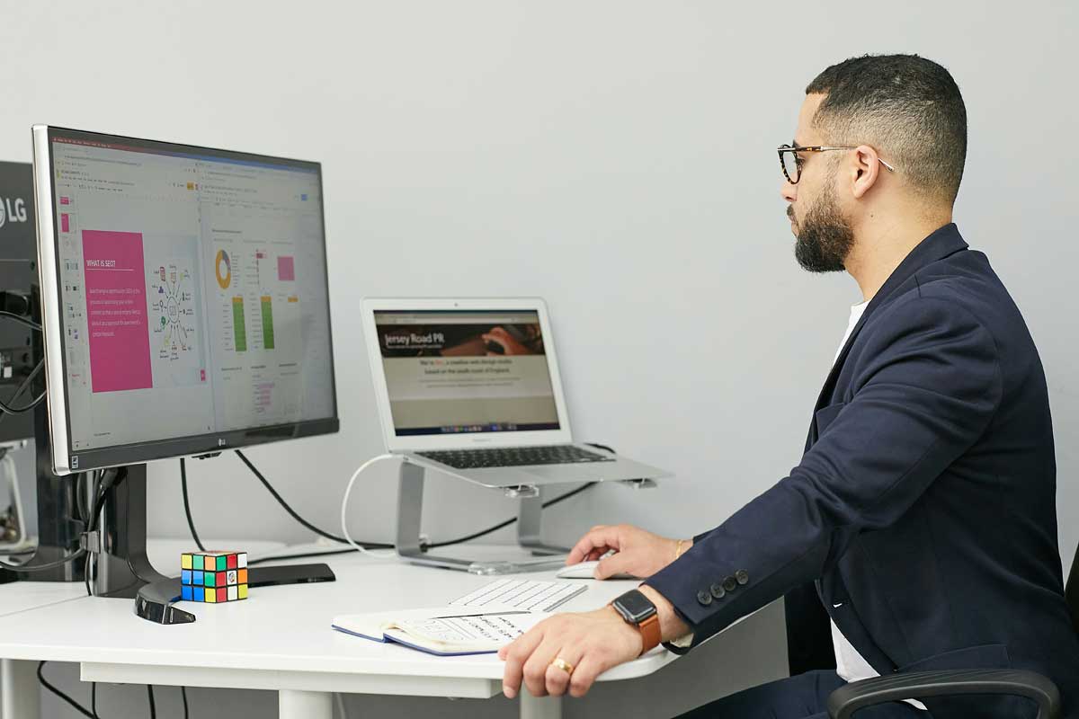  A man sitting at a desk with a laptop and a computer