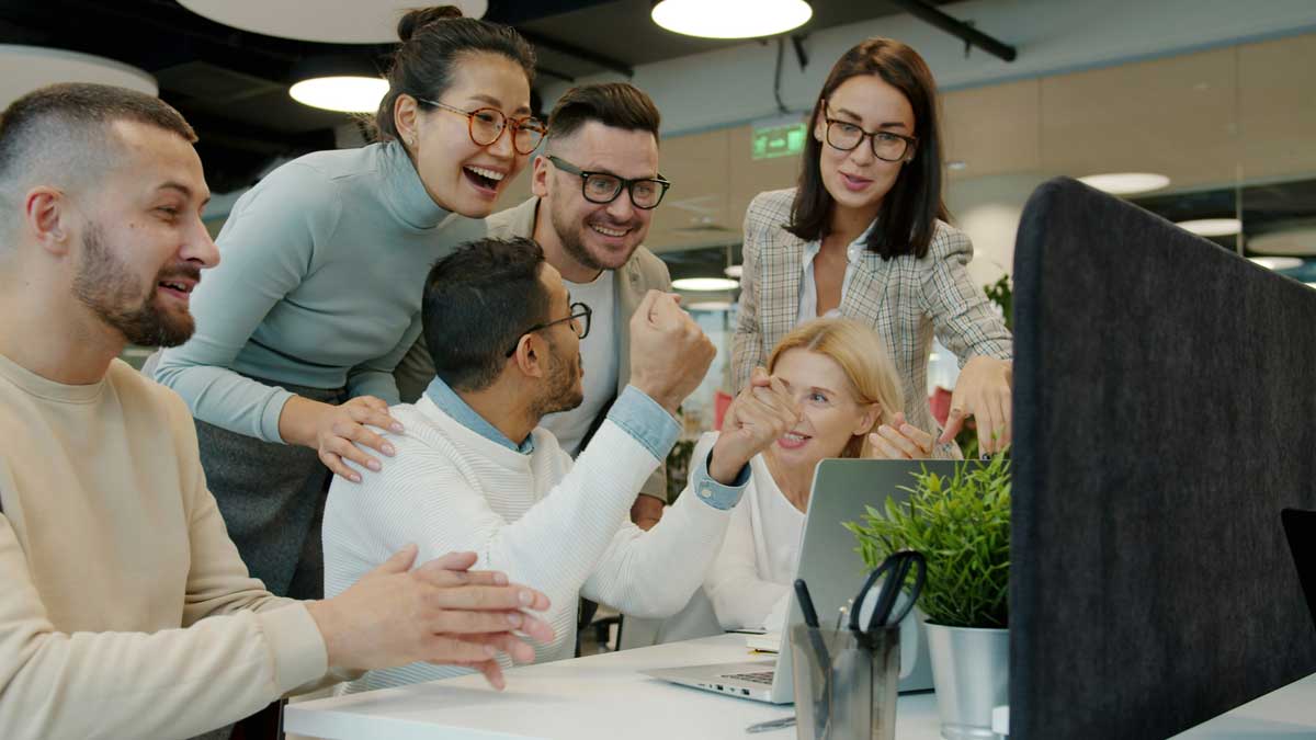 Multi-ethnic team women and men are talking clapping hands doing high-five celebrating achievement in open space office. People and work concept.