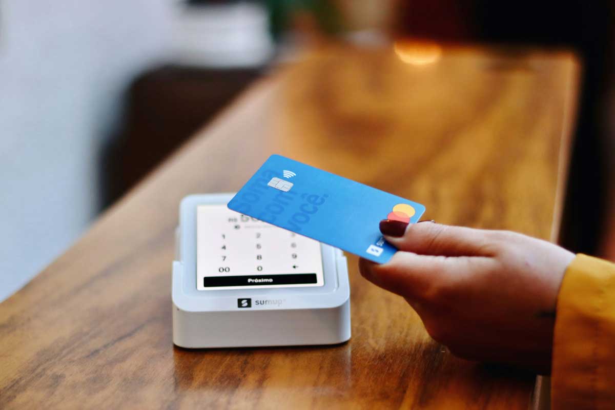 A person holding a credit card in-front of a machine