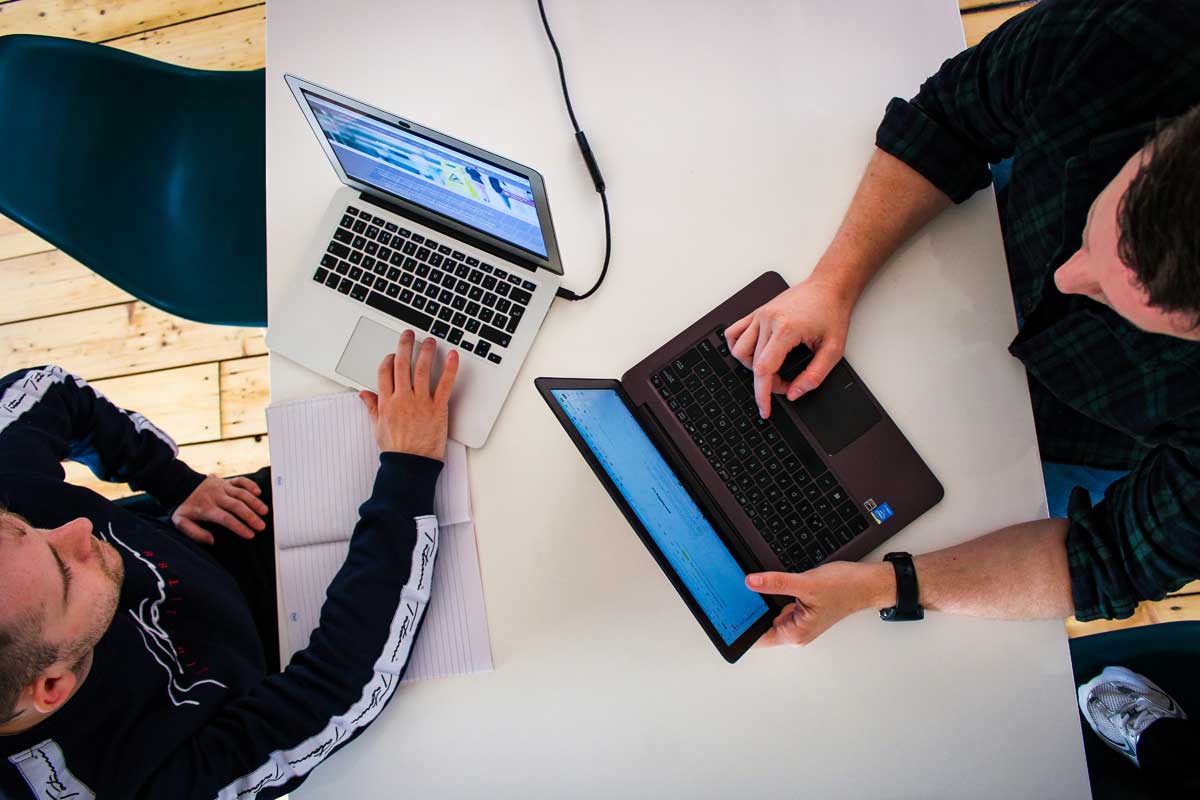 Digital marketing team in office working and reviewing client work on laptops
