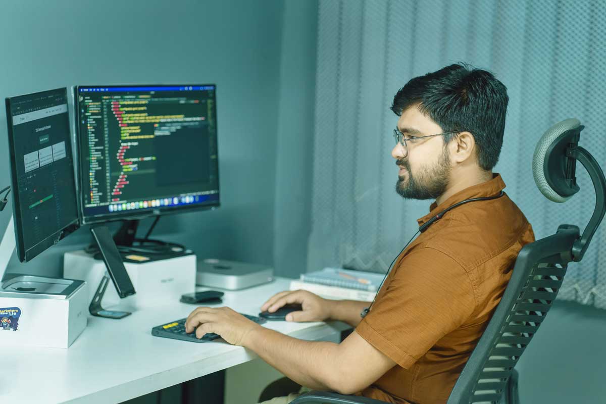 A focused developer coding at a modern office with dual monitors