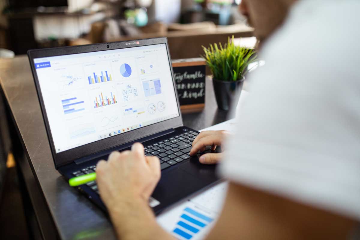Business analysis with charts and graphs on a laptop in a modern office setting.