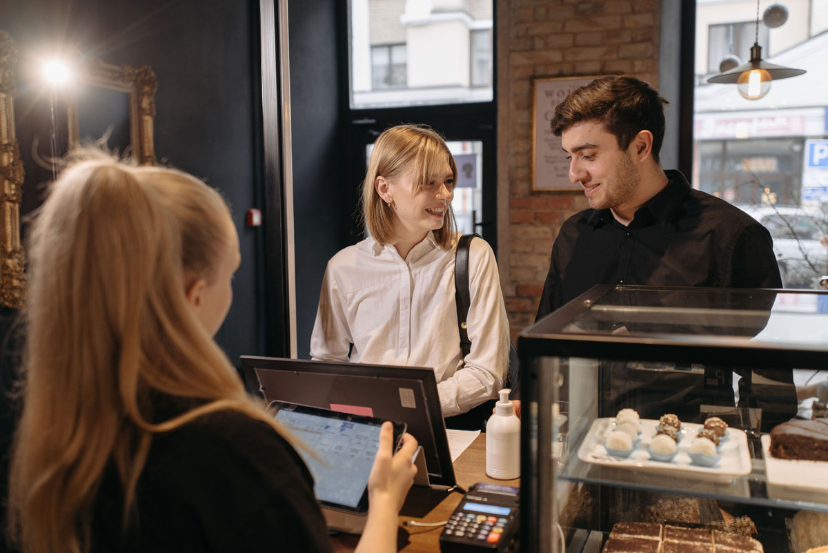 Customers interacting with a barista at a cozy coffee shop counter.