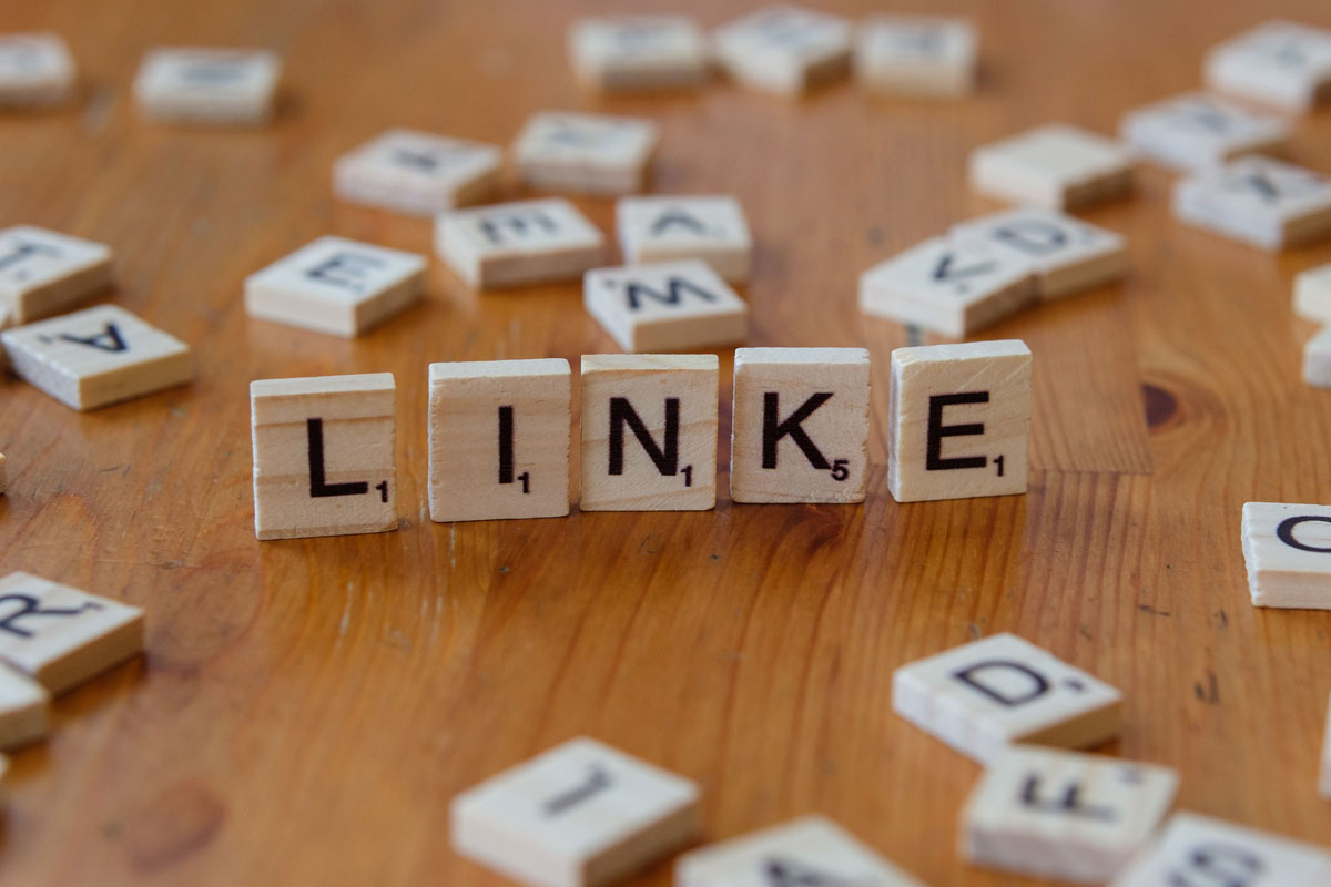 Scrabble tiles arranged to spell 'LINKE' on a wooden table, surrounded by scattered letters