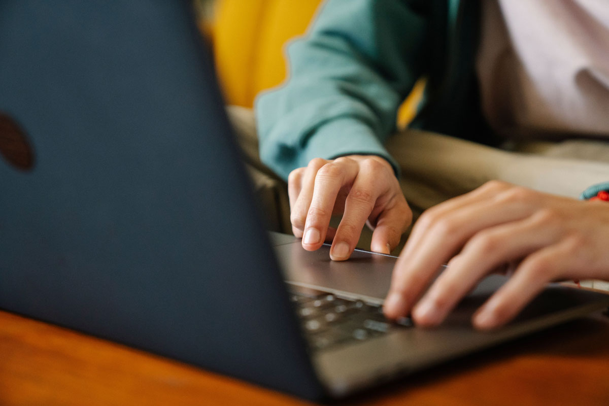 An individual typing on a laptop, focusing on the hands and keyboard in an indoor setting