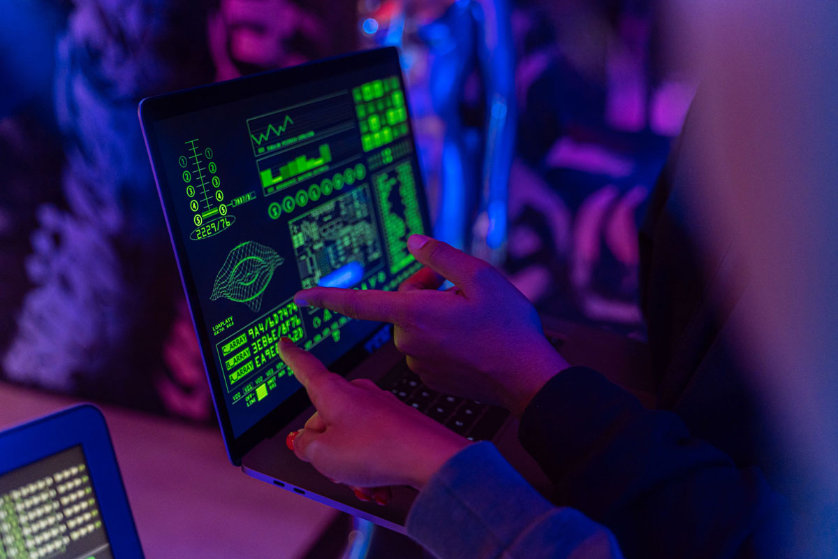 A person analyzing cybersecurity data on a laptop in a dimly lit room