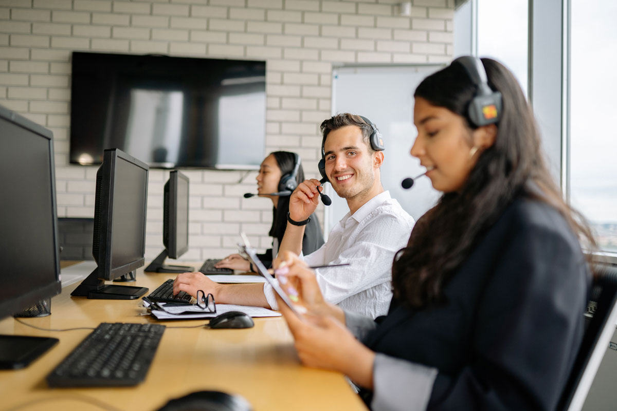 Smiling call center agents wearing headsets, working together in a modern office setting