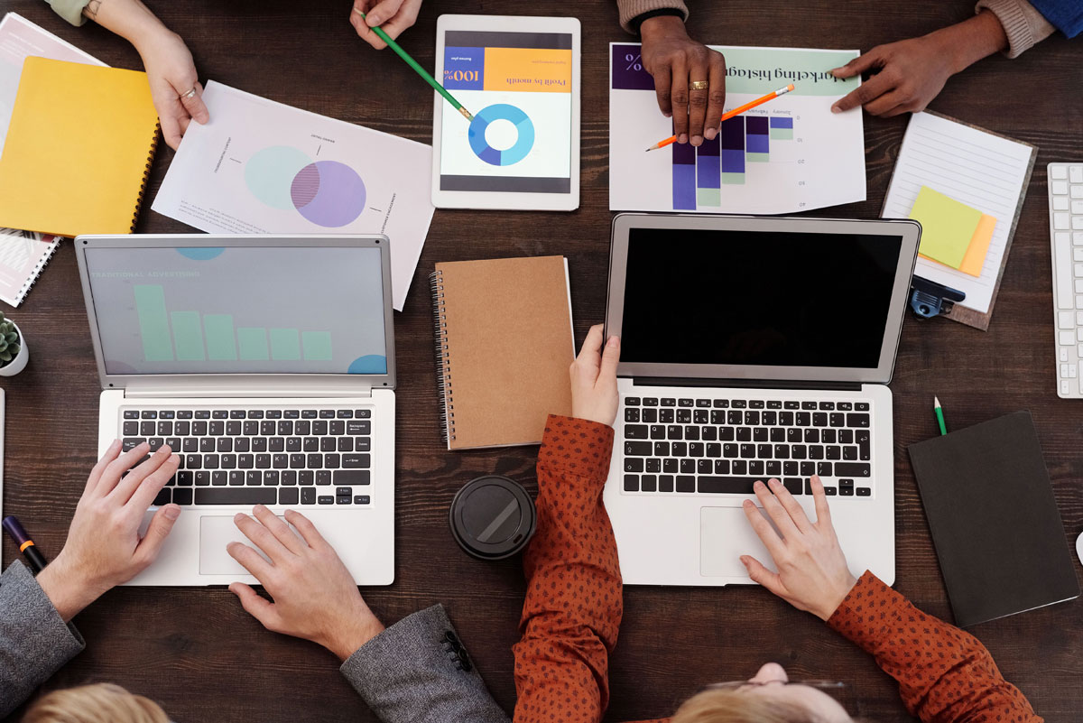 Overhead view of a team discussing digital marketing strategies with laptops and charts