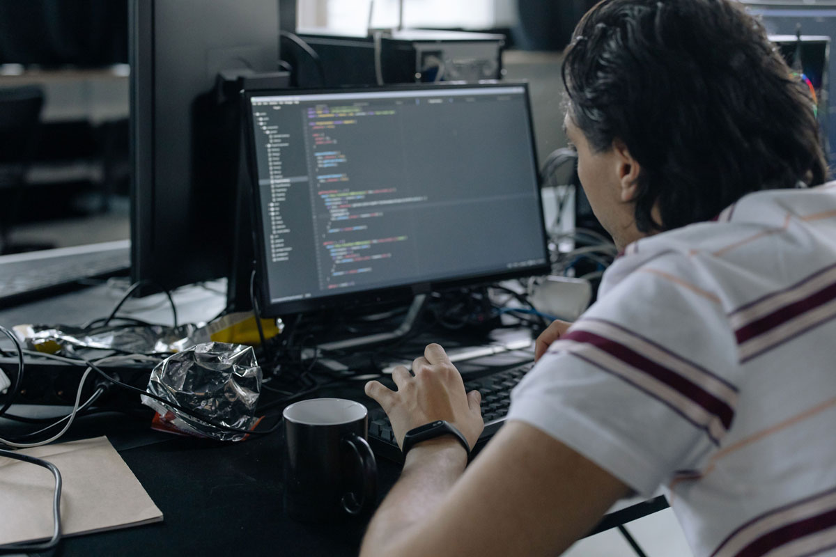 Man focused on coding at his workstation in a modern office