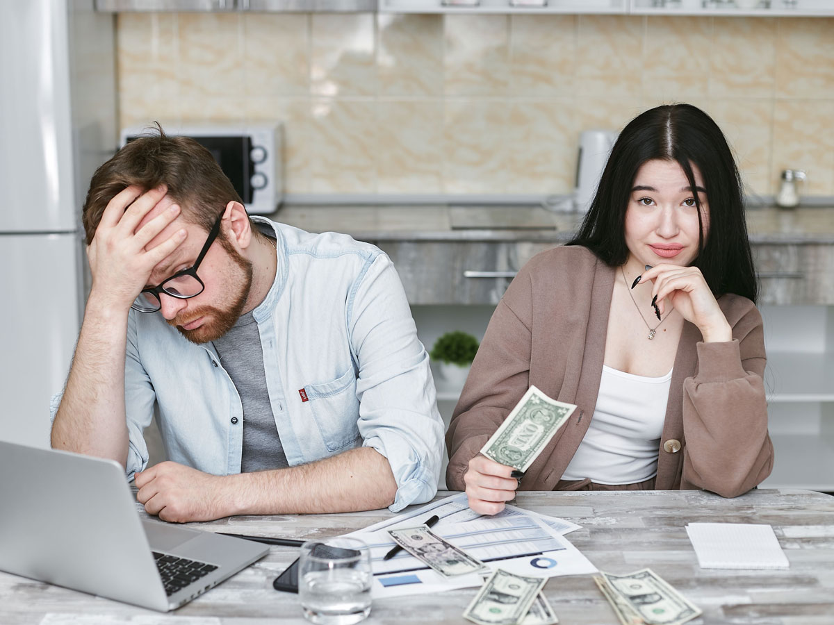 A couple managing their finances in a kitchen setting, showcasing money, debt, and budgeting challenges