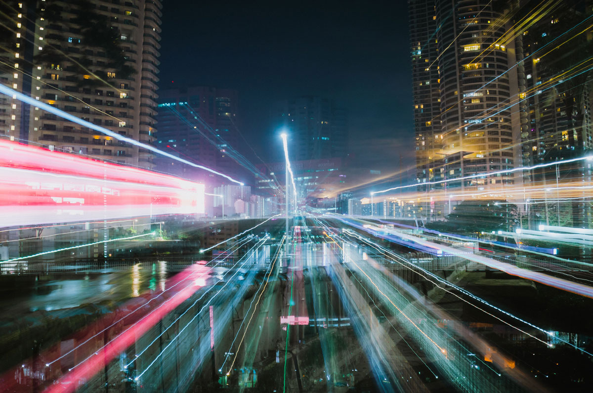 Vibrant urban landscape with dazzling light trails and skyscrapers at night.