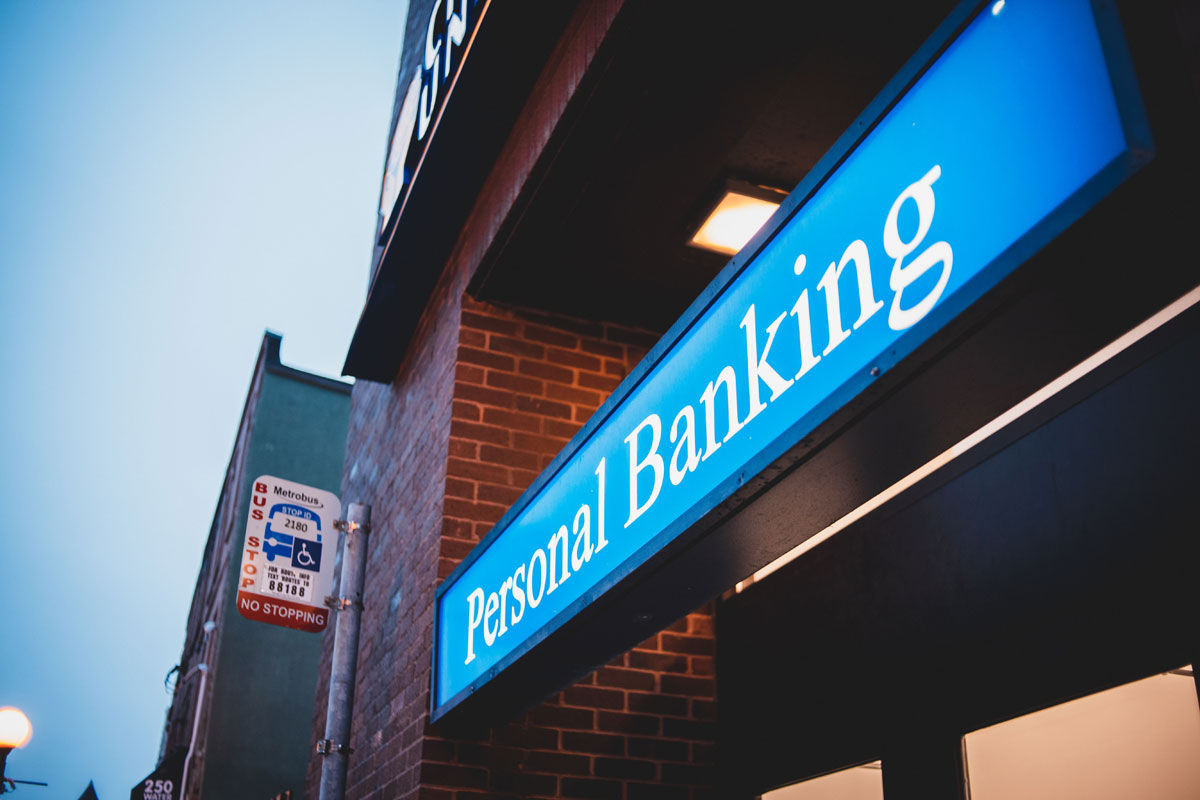 Low angle view of a personal banking sign in a city setting at dusk