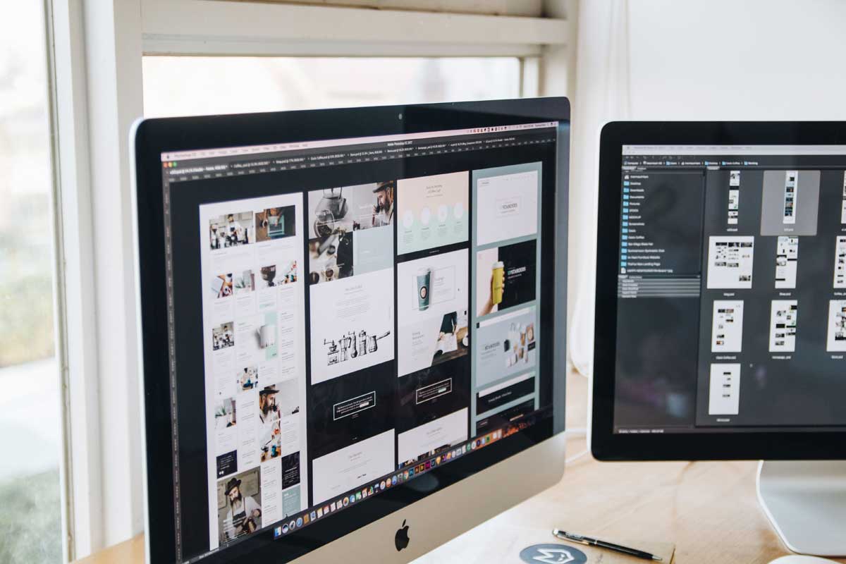 Modern office desk setup with dual monitors displaying design software