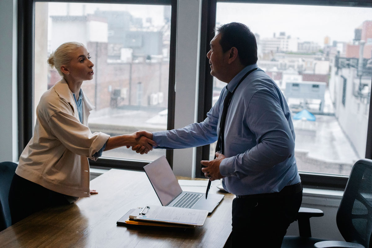 Professional handshake between two colleagues in a modern office setting.