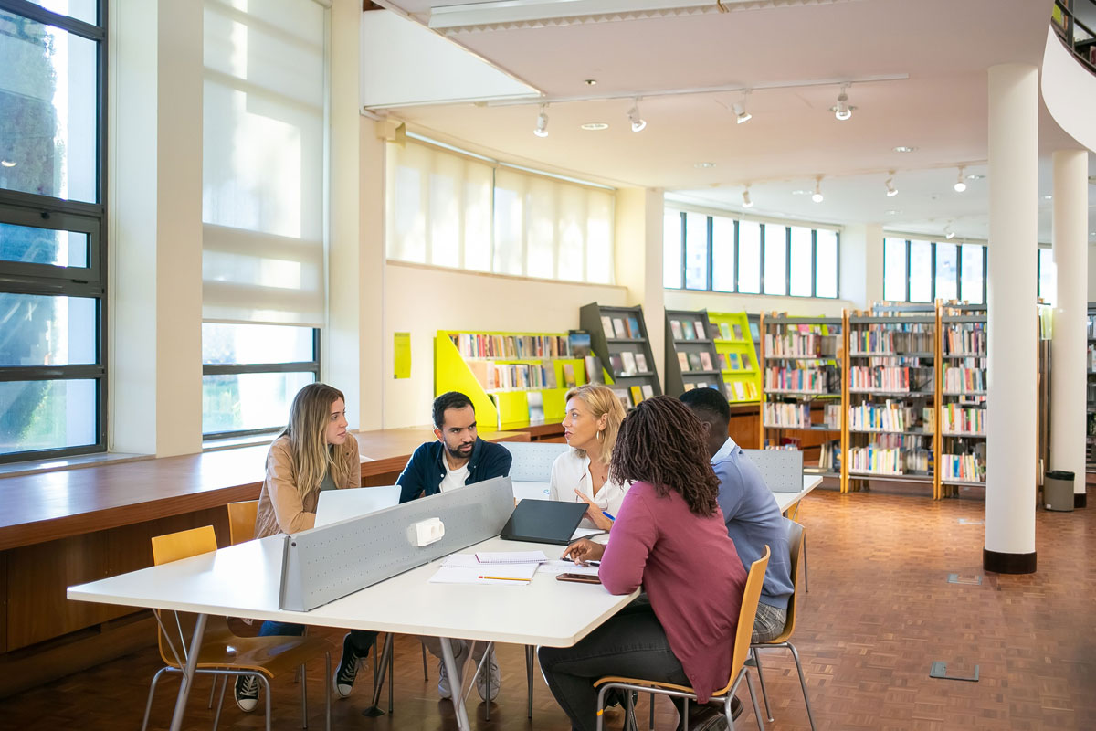Group of diverse university students collaborating during a study session in a library setting.